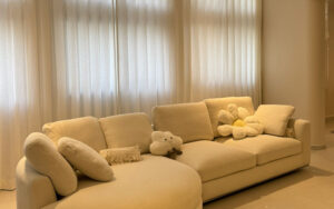 Cozy living room featuring soft cream-colored curtains and modular sofa.