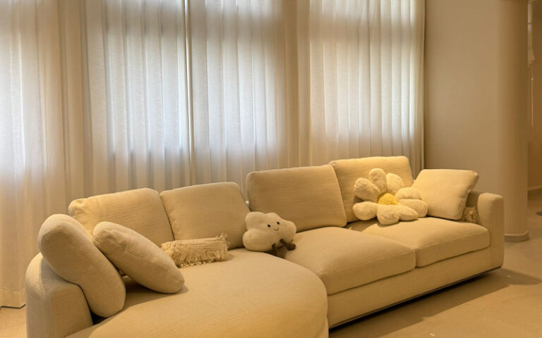 Cozy living room featuring soft cream-colored curtains and modular sofa.