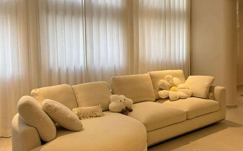 Cozy living room featuring soft cream-colored curtains and modular sofa.