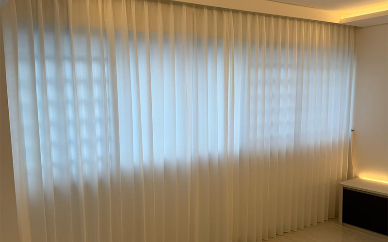Floor-to-ceiling sheer curtains covering a large window in soft light.