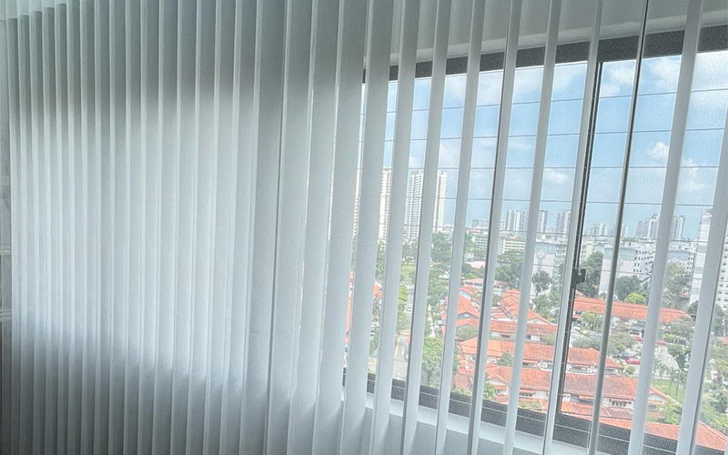 City view through window blinds with tall buildings.