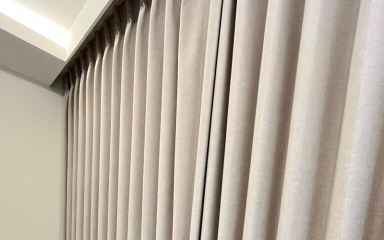 Close-up of elegant pleated curtains in a neutral beige tone.