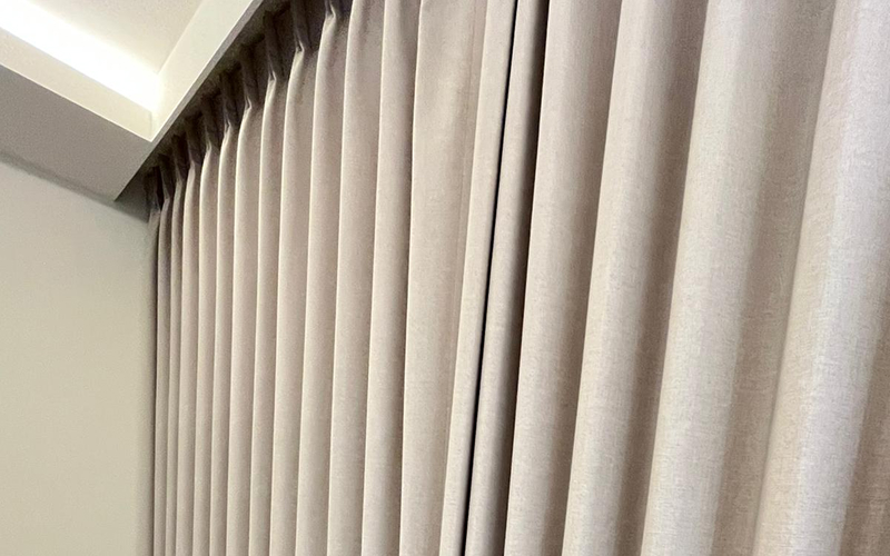 Close-up of elegant pleated curtains in a neutral beige tone.