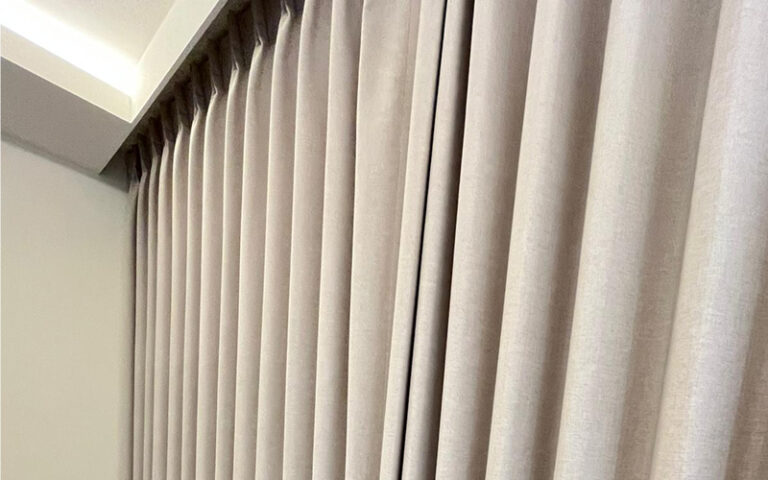 Floor-to-ceiling beige blackout curtains hung in a residential room.