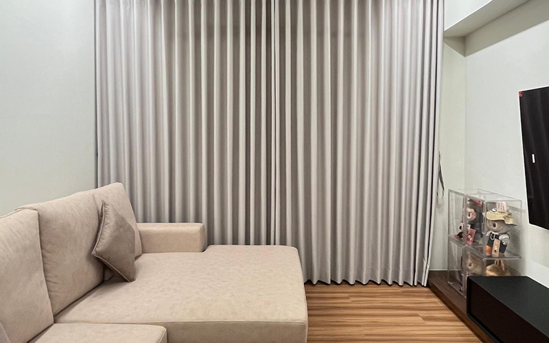 Full-length light grey blackout curtains installed in a modern living room.